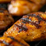 Side view of succulent grilled chicken served with fresh herbs.