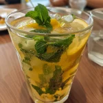 Mocktail vibrante e gelado de limão com detalhes de hortelã fresca.