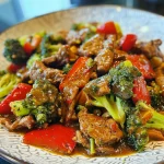 Prato de refogado de carne e brócolis visto de lado, focado nos ingredientes.