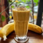 Frosted glass filled with a creamy, tropical smoothie featuring pineapple and banana.