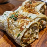 Delicious creamy chicken wrap displayed on a wooden surface.