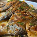 Peixe assado no forno, decorado com limão e ervas, em uma travessa.