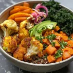 Uma tigela colorida de vegetais assados com quinoa, abacate e sementes de abóbora.