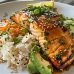 Close-up de um prato de salmão com manteiga de alho, arroz e legumes frescos.