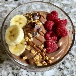 Tigela de iogurte de chocolate com frutas e granola.