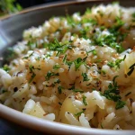 Close-up de arroz alho e óleo em um prato, com alho dourado visível.