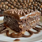 Bolo de cenoura coberto com brigadeiro e gotas de chocolate em um prato.
