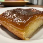 Close-up side view of a moist Bolo de Fubá Cremoso with a golden crust.