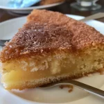 Fatia de Bolo fofinho de maçã com canela, mostrando camadas úmidas e pedaços de maçã.