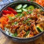 Um close de um bowl de frango agridoce com arroz, legumes frescos e molho.