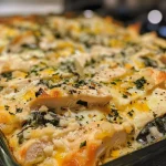 Casserole de frango com espinafre, coberta com queijo cheddar derretido.