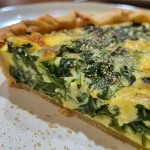 Lado da quiche de espinafre, revelando textura dourada e ingredientes.