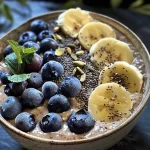 Smoothie bowl com camadas de banana e mirtilo, coberto com chia e frutas frescas.
