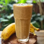 Close-up of a vibrant smoothie made with papaya and banana, served in a clear glass.