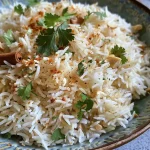 ['Prato de arroz de coco indiano com especiarias e ingredientes.', 'Close de arroz basmati cozido com coco e temperos.', 'Arroz aromático de coco indiano com pedaços de tomate e caju.', 'Prato colorido de arroz de coco com ervas e especiarias.']
