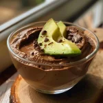['Mousse de chocolate e abacate em um recipiente, com textura cremosa.', 'Close de mousse de chocolate e abacate, com acabamento suave.', 'Mousse de chocolate e abacate, servido em uma taça, com decoração minimalista.', 'Deliciosa mousse de chocolate e abacate, vista lateral mostrando a cremosidade.']