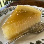 ['Pudim de limão saudável com cobertura de raspas de limão.', 'Vista lateral de um pudim de limão saudável em prato.', 'Pudim de limão decorado com raspas de limão fresco.', 'Close de pudim de limão saudável servido em mesa.']