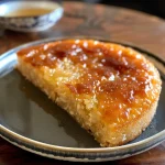 ['Bolo de ameixa simples fatiado, exibindo a textura e os pedaços de fruta.', 'Bolo de ameixa sem trigo em um prato, com fatias expostas ao lado.', 'Close de um bolo de ameixa, destacando a umidade e a crocância da cobertura.', 'Porção de bolo de ameixa simples, mostrando a mistura de farinhas e ameixas.']