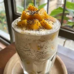 ['Bebida espessa de café da manhã com manga e sementes de chia.', 'Close de um copo com bebida de manga e chia.', 'Bebida refrescante de coco, manga e chia em copo.', 'Mistura de chia e manga em bebida saudável.']