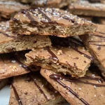 ['Biscoito integral recheado com chocolate em close-up.', 'Lado de um biscoito integral com recheio de chocolate.', 'Biscoito integral crocante com chocolate ao fundo.', 'Detalhe de biscoito integral com chocolate recheado.']