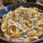 ['Um prato de fettuccine coberto com molho de gorgonzola, decorado com salsinha.', 'Close de fettuccine ao molho cremoso de gorgonzola, com uma camada de queijo.', 'Fettuccine servido em prato, envolto em um molho azul de gorgonzola.', 'Detalhe de fettuccine ao molho de gorgonzola, com salsinha fresca por cima.']