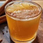 ['Mocktail de cidra de maçã com canela e gengibre.', 'Bebida refrescante de cidra de maçã em copo.', 'Close de um mocktail de cidra de maçã.', 'Drink de cidra de maçã servido com especiarias.']