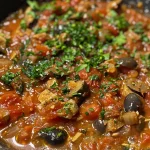['Molho puttanesca saboroso em uma tigela.', 'Close up de molho puttanesca com ingredientes visíveis.', 'Tigela de molho puttanesca com azeitonas e alcaparras.', 'Molho puttanesca fresco e colorido em fundo claro.']