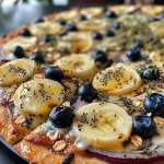 ['Fatia de pizza de melancia com cobertura de frutas e granola.', 'Pizza de melancia decorada com coco, mirtilos e manga.', 'Close-up de pizza de melancia com ingredientes naturais coloridos.', 'Pizza de melancia em uma mesa, rodeada de frutas frescas.']