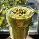 ['Smoothie de pistache com frutas em um copo.', 'Close-up de um smoothie verde cremoso de pistache.', 'Bebida refrescante de pistache com pedaços de frutas.', 'Copo de smoothie de pistache decorado com frutas.']