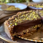 ['Torta de chocolate e pistache vista de lado, com textura cremosa.', 'Close up de Torta de chocolate com cobertura de pistache, apetitosa e suculenta.', 'Torta de chocolate e pistache em uma apresentação elegante, com camadas visíveis.', 'Lado da Torta de chocolate e pistache, destacando a crocância da base e a cremosidade.']