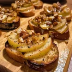 ['Bruschetta de maçã e canela com fatias de baguete.', 'Close-up de bruschetta com recheio de maçã e canela.', 'Imagem de bruschetta de maçã com cobertura crocante.', 'Bruschetta de maçã e canela servida em uma tábua.']