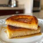 ['Pudim de abóbora cremoso com calda caramelizada.', 'Close-up de pudim de abóbora em prato, com textura suave.', 'Pudim de abóbora amarelo, decorado com canela.', 'Vista lateral de um pudim de abóbora, evidenciando a calda.']